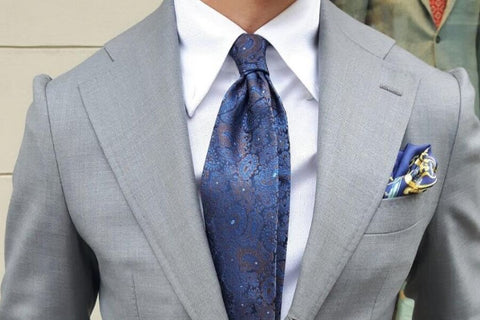 Costume gris clair et cravate bleue à motifs cachemire.