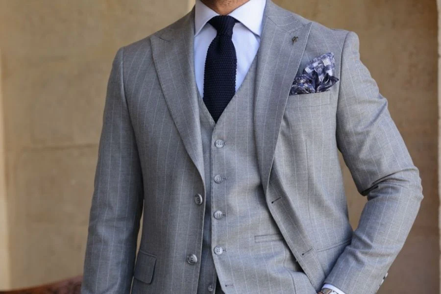 Costume gris clair à rayures et cravate en maille bleu marine.