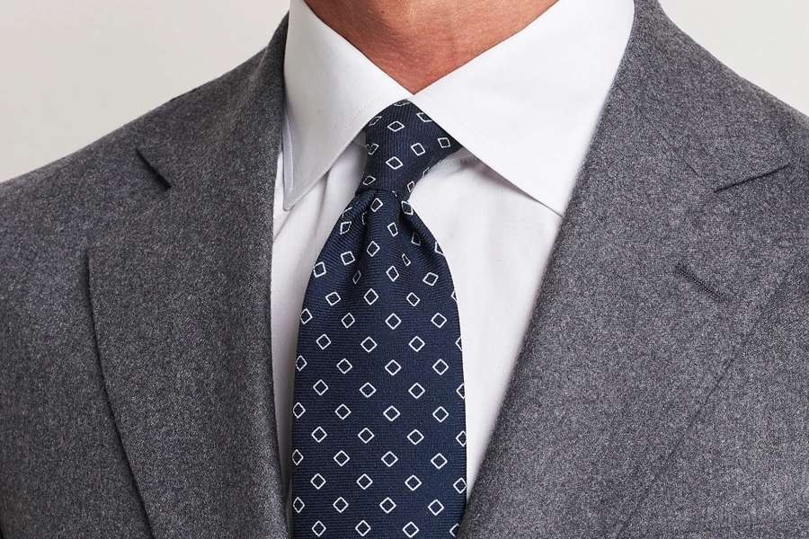 Costume gris clair à rayures et cravate en maille bleu marine.