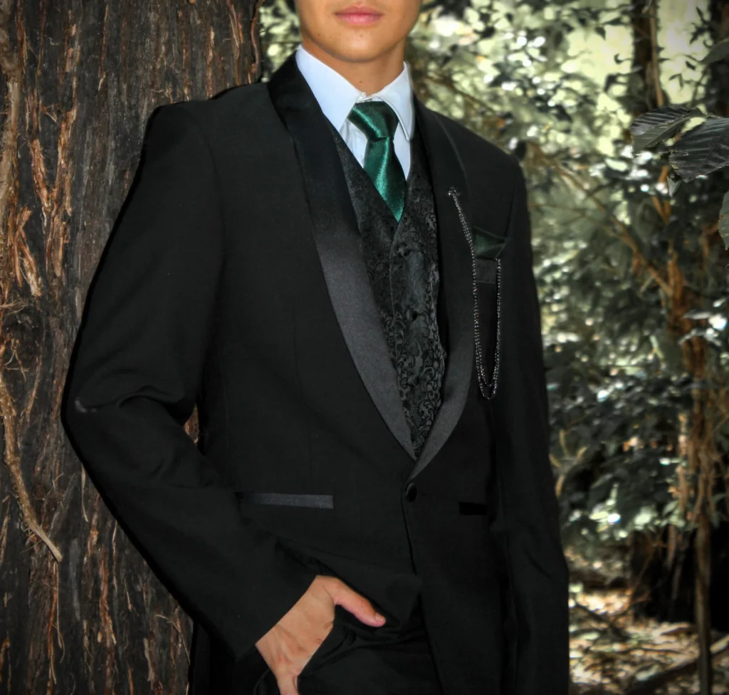 Costume noir parfaitement structuré, rehaussé d’un gilet à motifs ton sur ton et d’une cravate vert émeraude. Une silhouette sophistiquée, à la fois classique et contemporaine, qui évoque une élégance formelle maîtrisée jusque dans les moindres détails.